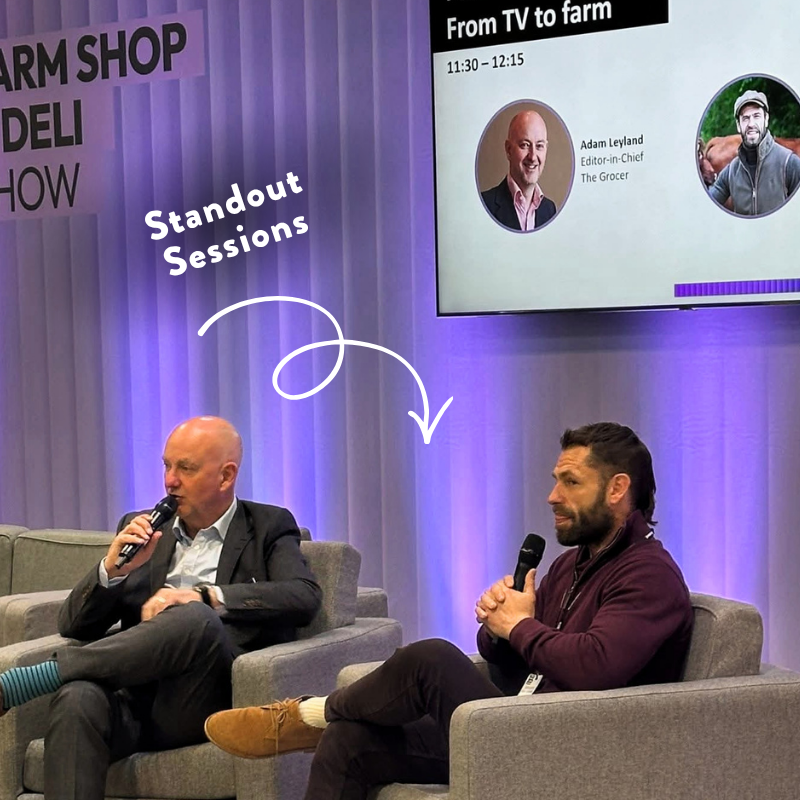 Guest speaker seated on stage during a live talk at the Farm Shop & Deli Show, with presentation screen behind.