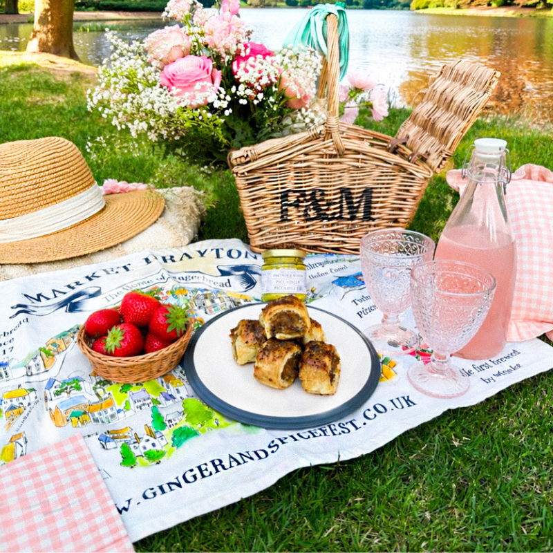 Picnic scene with gingerbread sausage rolls, strawberries, pink lemonade and Billington’s hamper by lakeside