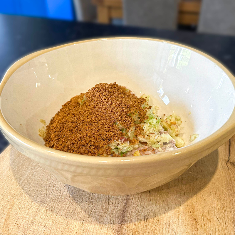 Mixing bowl with sausage meat, grated apple, spring onion and Billington’s gingerbread crumbs ready to combine